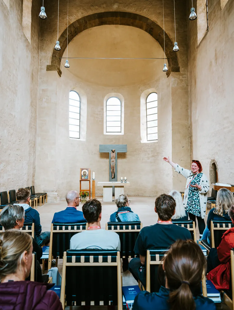 In der Klosterkirche spricht eine Frau vor dem Altarraum zu den Teilnehmenden